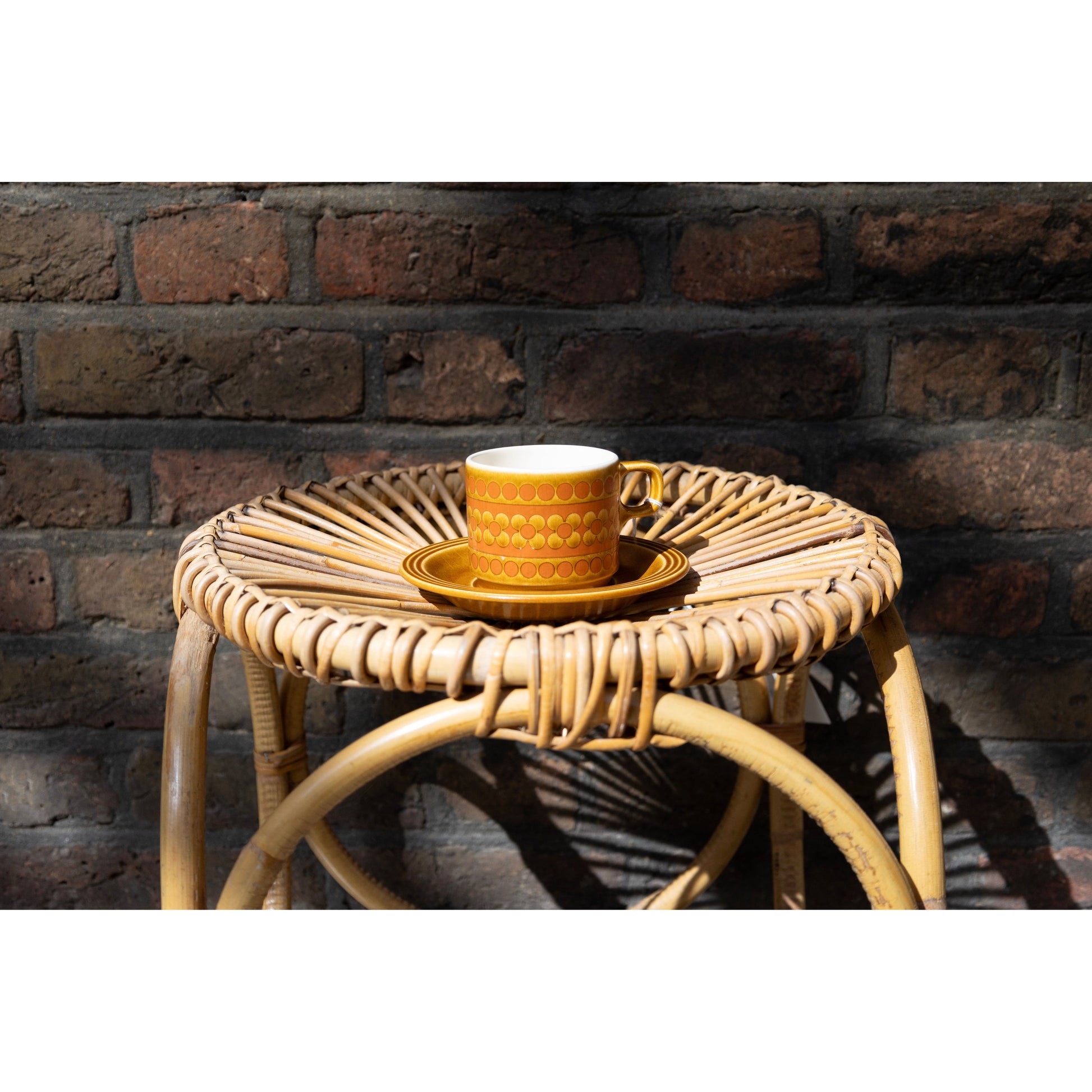 Yellow mug on a woven stool against a brick wall