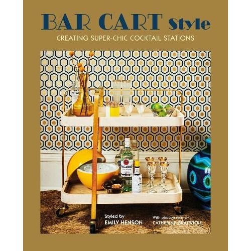 A golden book cover with a photography of a bar cart in a 70s style. You can see bottles of different liquors, ice and glasses. The wall paper of the photograph is in classic 70s colors: yellow, blue and white.  On the top in blue text it reads: "Bar Cart Style" and below in white font "Creating super-chic cocktail stations."