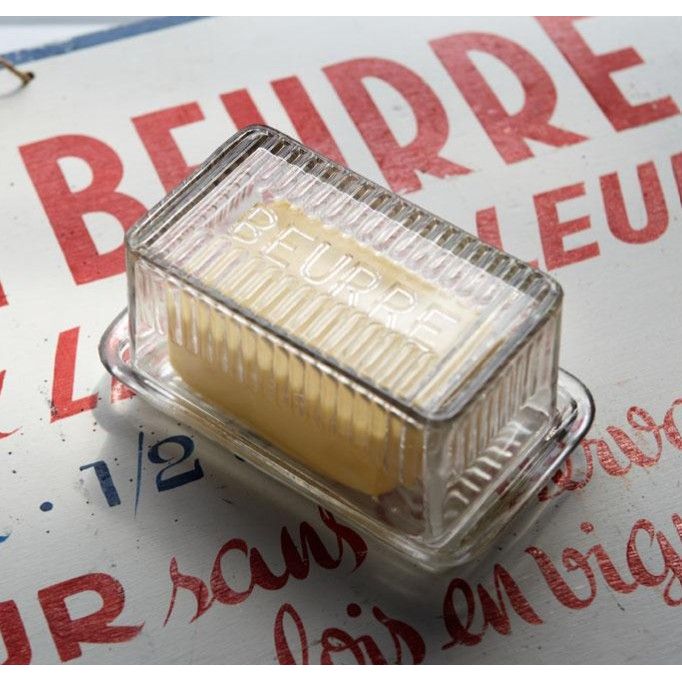 Butter dish with a stick of butter on a surface with text