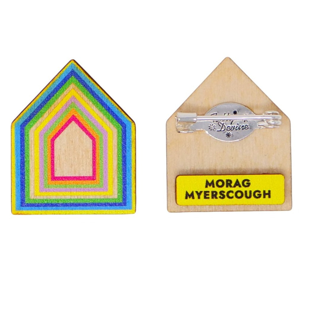 Wooden brooch in the shape of a house with colourful borders seen from the front and the back. Back features the text "Morag Myerscough".