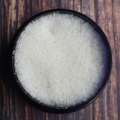 Open tub of a white hand scrub; background shows a wooden table.