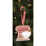 A decoration simulating a baking mixer hanging on a tree. The ribbon from which it hangs is red and white squares.