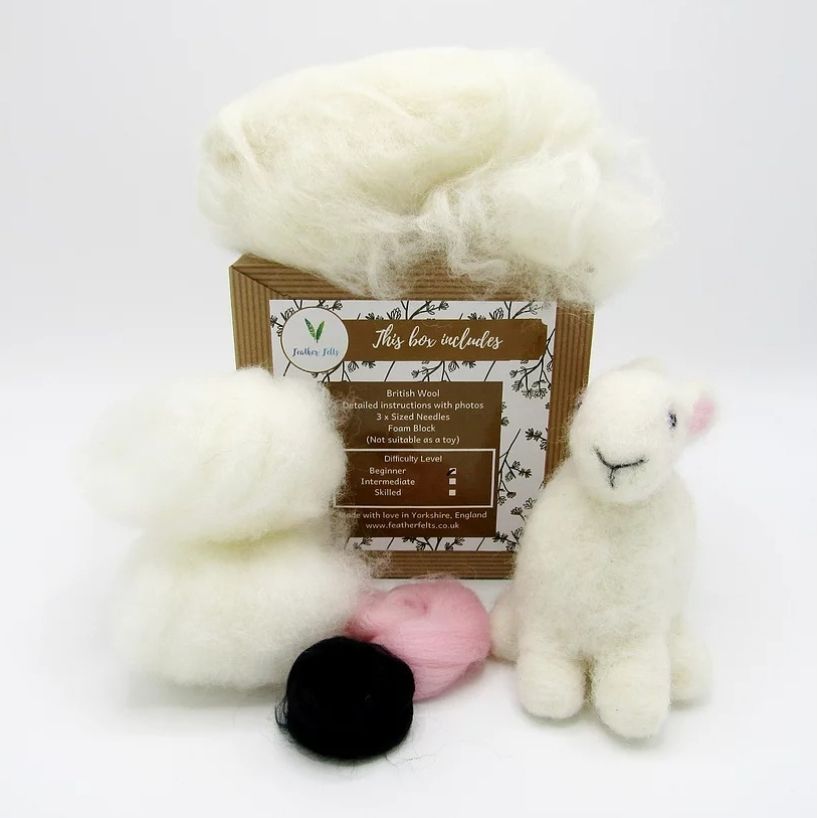 White fluffy material, small bunny toy, and black and pink felt bundlles on a white background with a label.