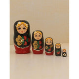 Five matryoshka dolls on a beige background. The dolls are painted in black and red clothes and are holding strawberries.