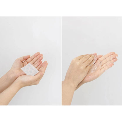 Hands holding a small white paper and then rubbing it on hands against a light gray background
