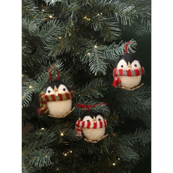 Three penguins hanging on a Christmas tree. Each penguin is wearing a different scarf colour, one is red and green, one is red and white and one is red and grey.