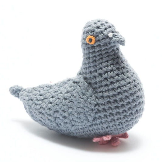 A light blue-gray crocheted pigeon plush toy with a small orange and black eye, white beak, and pink feet, shown on a white background.