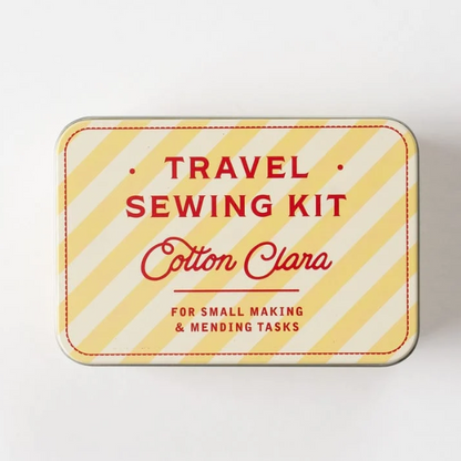 A square metal tin labeled 'Travel Sewing Kit' with 'Cotton Clara' in red script. The tin has a yellow and white diagonal striped pattern with red text and a red dashed border, photographed on a plain white background.