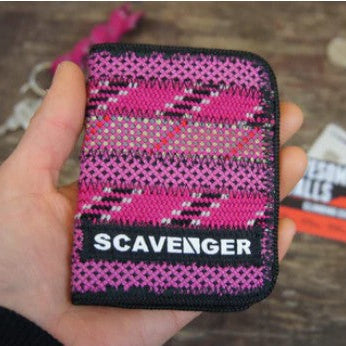 Pink and black patterned Scavenger product held in a hand on a textured surface.