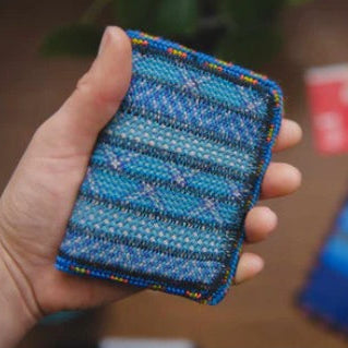 Hand holding a blue textured fabric item with a blurred background
