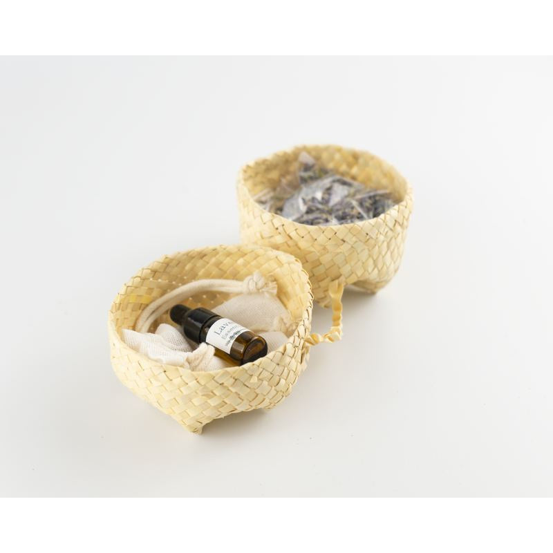 An open small basket with lavender oil inside and a muslin bag.