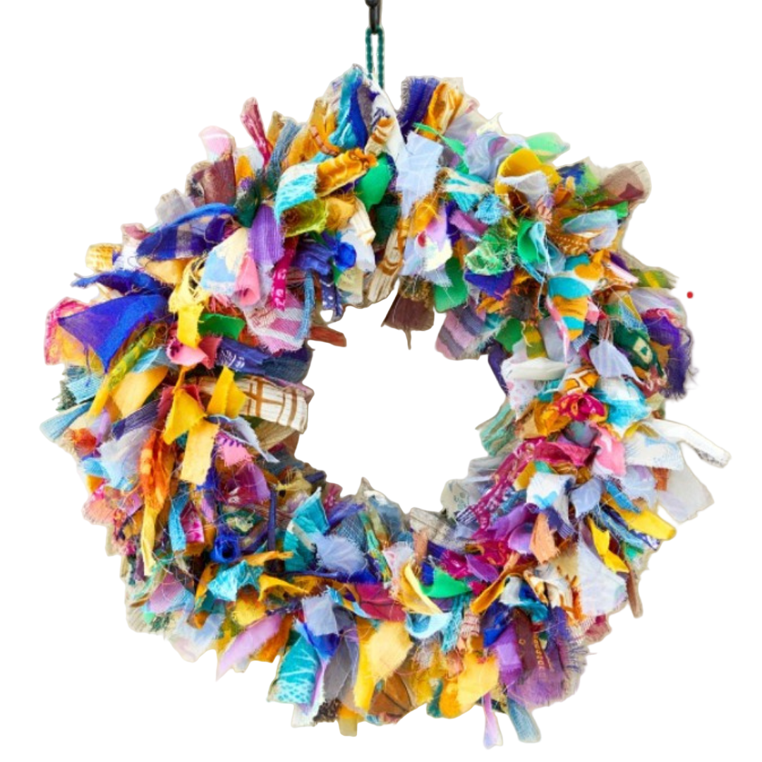 Colorful recycled fabric wreath hanging on a white wall