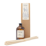 Diffuser oil in scent 'black pomegranate' in brown glass container; diffuser sticks in front of cardboard packaging with 'apothecary' design on label.