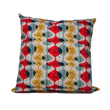 Cushion cover with white background and fluid red, green and yellow ovoid shapes with black atomic structures. 