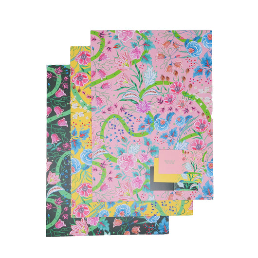 3 sheets of gift wrap, one with light pink background, one yellow and one black. All have pattern of pink, red and blue flowers with green stems and swirled lines.