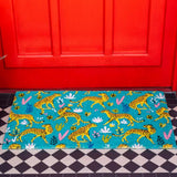 Green and yellow doormat with illustrated cheetahs; background is a red door and a black and white porch.