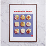 On a white marbled background, there is a frame with the print of the Mooncake Guide in it.