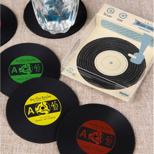 Three coasters in the shape of records. One green, one yellow and one red. In the middle of each one it reads 